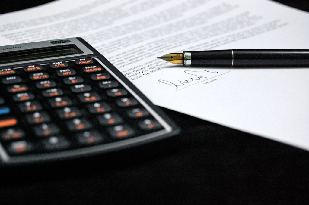 Un papel, un boligrafo y una calculadora encima de una mesa