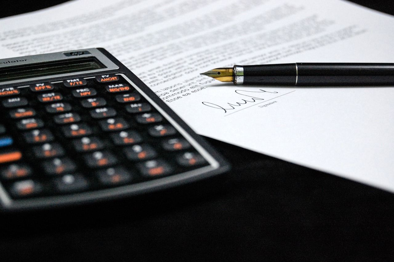 Un papel, un boligrafo y una calculadora encima de una mesa