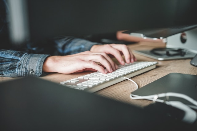Manos de una persona escribiendo en un teclado de una computadora