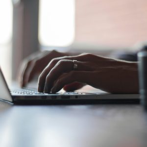 Manos de un hombre escribiendo en el teclado de una laptop