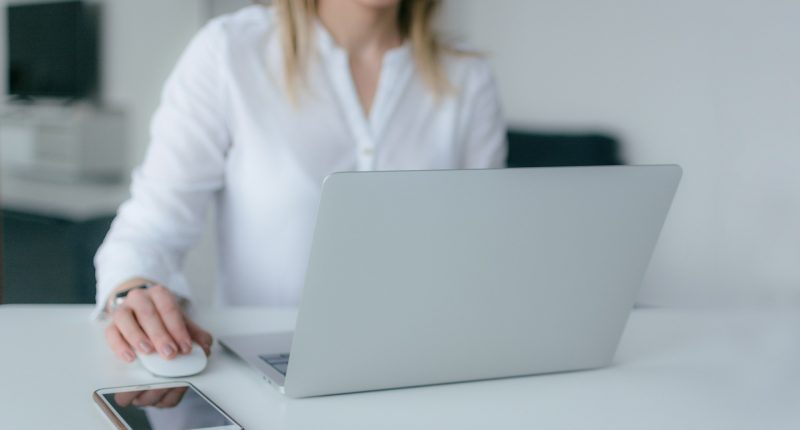 mujer con camisa blanca trabajando en una computadora