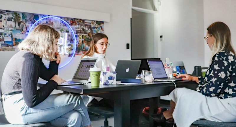 Tres mujeres trabajando en laptops en un escritorio